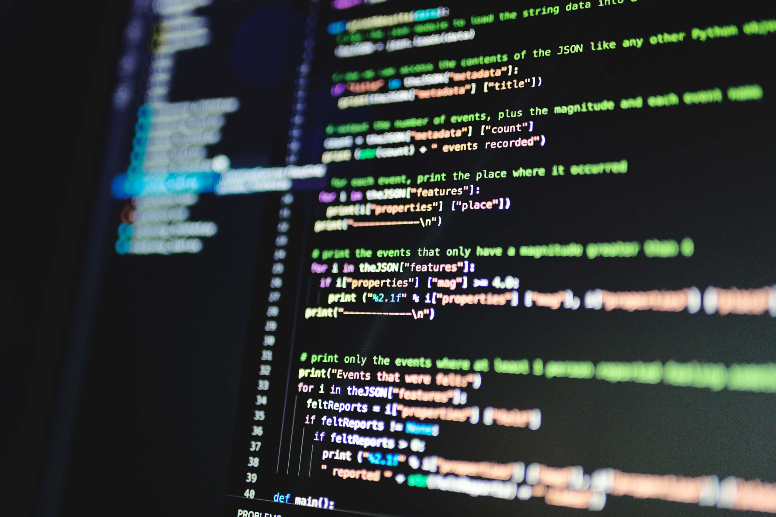 Programming code on a computer monitor in a dimly lit workspace